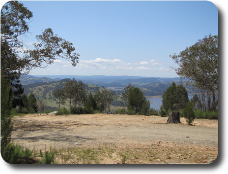 Lookout in foregrond, to water and rolling light green hills with dark green vegetation patches