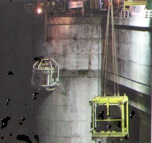 Night scene, bell on left, steel frame with concrete block, both against rear of dam wall