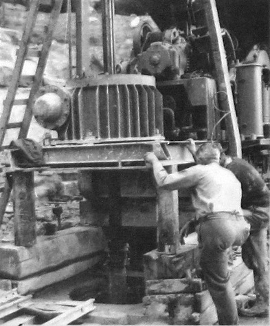 A couple of men with machine drilling vertically into ground