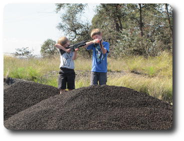 Two boys with toy guns on top of gravel mound