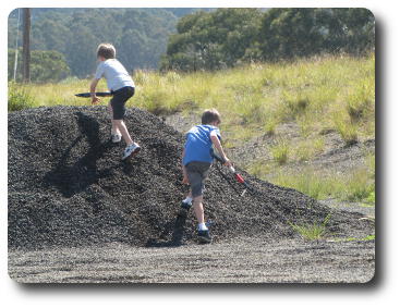 Two boys climbing mound to a secure position