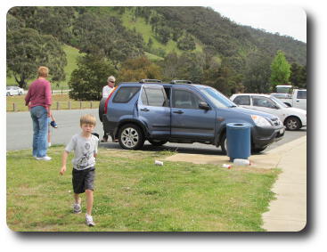 Car in parking area, boy running towards camera