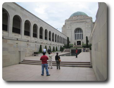 Long open stone corridor, cloisters each side, leading to domed building with memorial pool