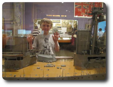 Little boy towering over model of ship