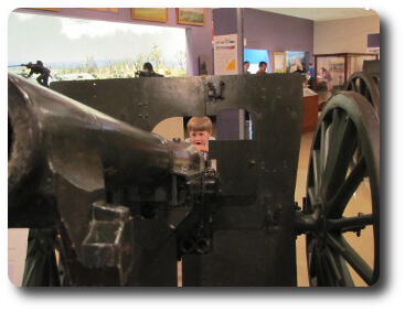 Boy peering through shield of artillery gun