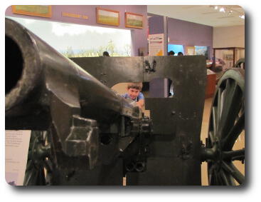 Boy peering through shield of artillery gun