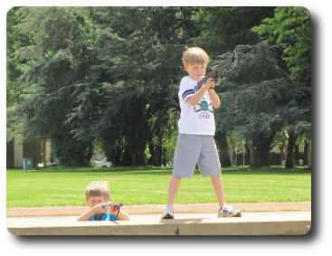 Two boys with rifles; one behind parapet, other standing on it