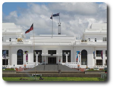 Entrance to white building with 3 flags visible on different poles