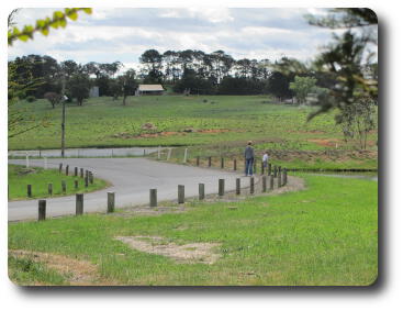 Country scene; distant farmhouse, lady and young boy near pond