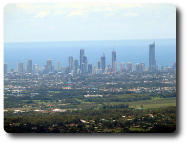 Tall buildings along the beach, housing and green areas closer to camera