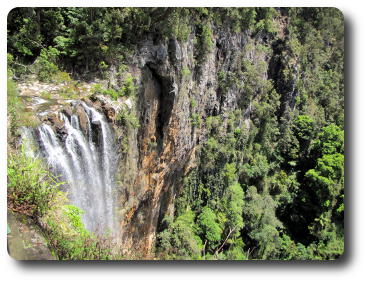 Small flow of water over falls to densely treed valley