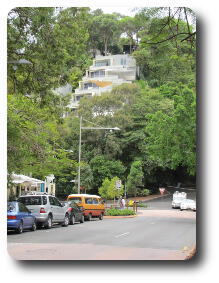 Apartments climbing hillside between tress in street