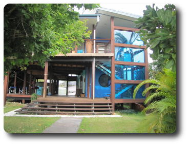 Two storey house with upper balcony, partly hidden behind trees