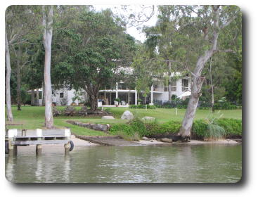 Large home nestled among trees near the river bank