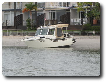 Small cabin cruiser stranded on beach in front of apartments