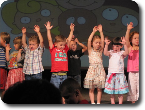 10 children on stage, hands above head