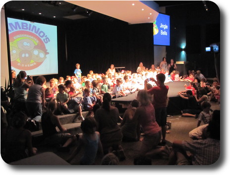 Stage full of children and a few adult assistants