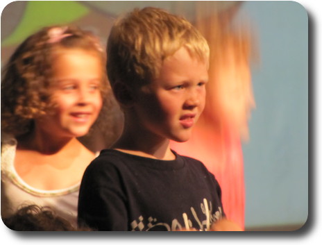 Close up of little boy with anxious look on face; little girl smiling behind