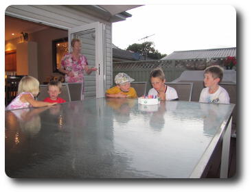 Five youngsters sitting at table with cake