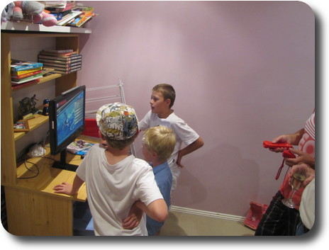 Boys in front of monitor, a couple of adults partly visible ehind