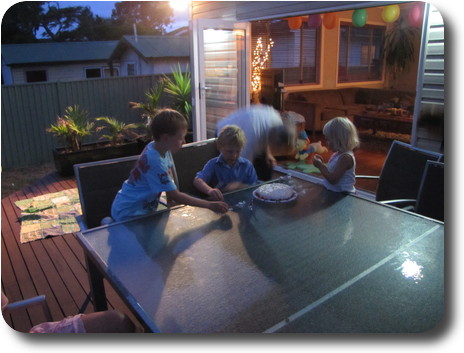 Children sitting at table with birthday cake