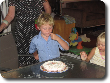 Little boy and girl next to table with cake