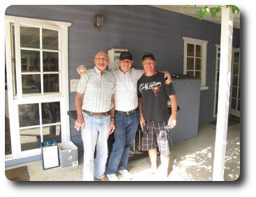 Three men in front of barbeque