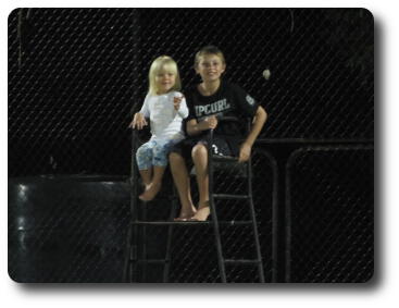 Little girl and boy on umpire's stand on tennis court