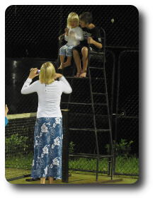 Woman taking photo of little girl and boy in umpire stand