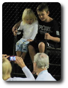 Mother and grandfather with little girl and boy in umpire stand