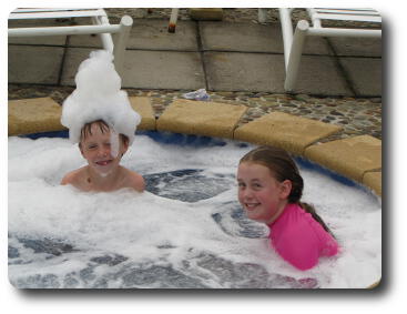 Young boy and girl in spa; boy has a soap suds crown