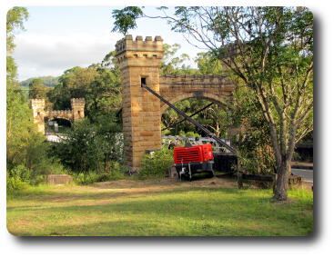 Side angle view of bridge with stone towers amid trees