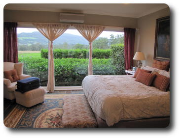 Bedroom with large windows looking to front lawn, distant hills