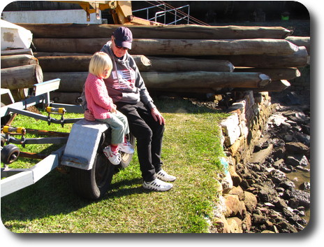 Grandfather and granddaughter sitting next to river bank