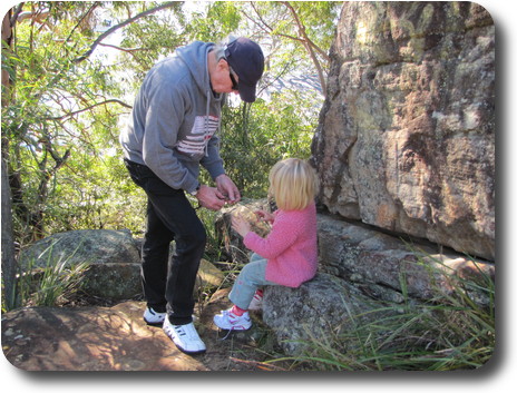 Grandfather helping granddaughter split long, narrow leaves