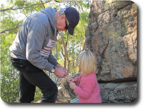 Grandfather helping granddaughter split long, narrow leaves