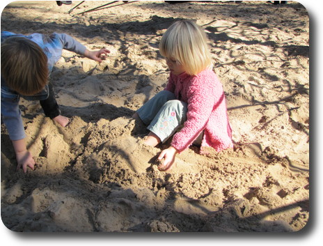 Little girl covering her feet with sand