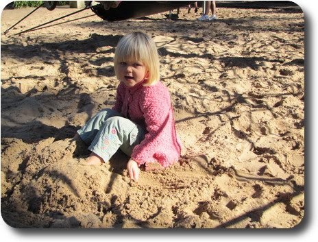 Little girl still moving sand to further cover her feet