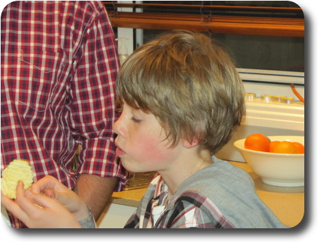 Boy with longish hair inspecting potato chip in his hands