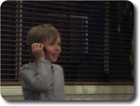 Little boy holding very small walkie talkie to his ear