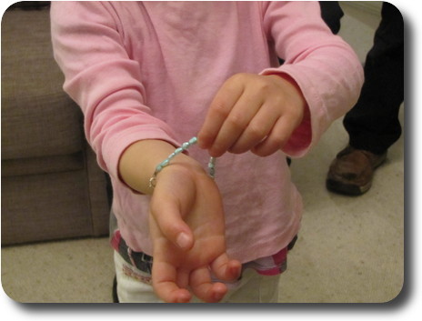 Little girl's arms and hands, showing off a bracelet