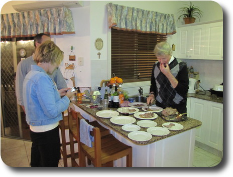 Two men and woman standing while serving dinner in kitchen