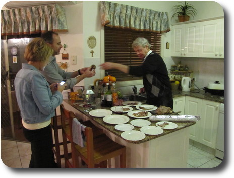 Carver handing sample of roast to other man in kitchen