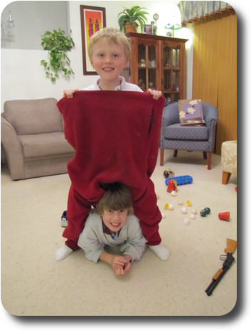 Little boy wearing jumper/pullover on his legs, another boy underneath