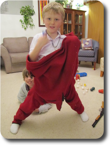 Little boy wearing jumper/pullover on his legs, another boy behind