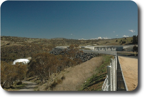 Top of dam wall on upstream side, and water gushing out downstream