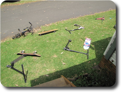 Skateboards, bikes and scooters on the lawn in front of cabin