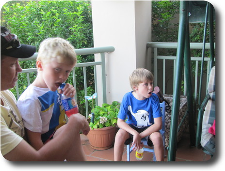 Man with boy on lap, and another boy with mouth open on small chair