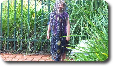 Little girl, with scarf covering her head to toe, in garden setting