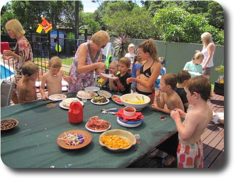 Woman serving ice cream cake to party goers, while others are already eating